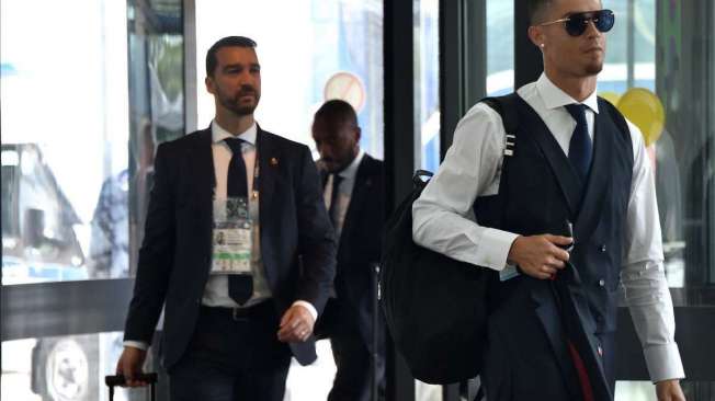 Portugal's forward Cristiano Ronaldo (R) arrives at the Zhukovsky airport, about 40 km southeast of Moscow, on July 1, 2018, as Portugal's team departs following their loss the previous day to Uruguay in their Russia 2018 World Cup round of 16 football match.  / AFP PHOTO / Vasily MAXIMOV
      Caption