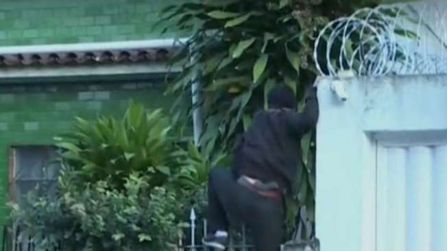 Agentes escalam muro da casa de um  acusado, que n�o foi encontrado