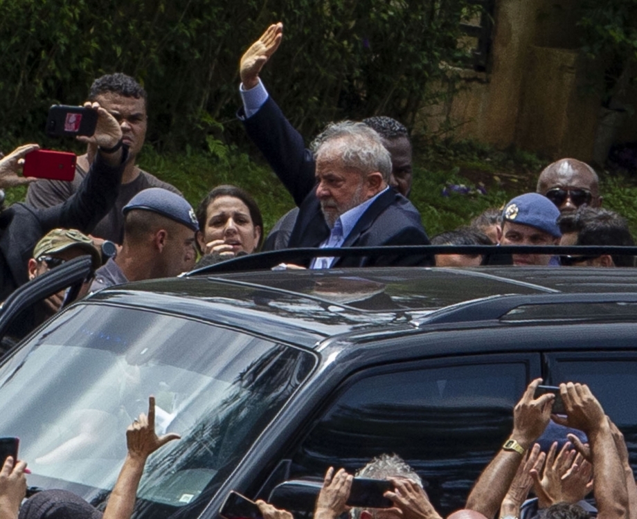 Brazilian former president (2003-2011) Luiz Inacio Lula da Silva (C) waves to supporters as he leaves the Jardim da Colina cemetery, in Sao Bernardo do Campo, Sao Paulo, Brazil where he attended his grandson's funeral on March 2, 2019, after a federal court authorised his release for a few hours from the Federal Police headquarters in Curitiba, Parana state, where he is serving a 12-year prison sentence. - Brazil's jailed former president Luiz Inacio Lula da Silva on Friday was granted leave from prison to attend the weekend funeral of his young grandson, who died at the age of seven. (Photo by Miguel SCHINCARIOL / AFP)
      Caption