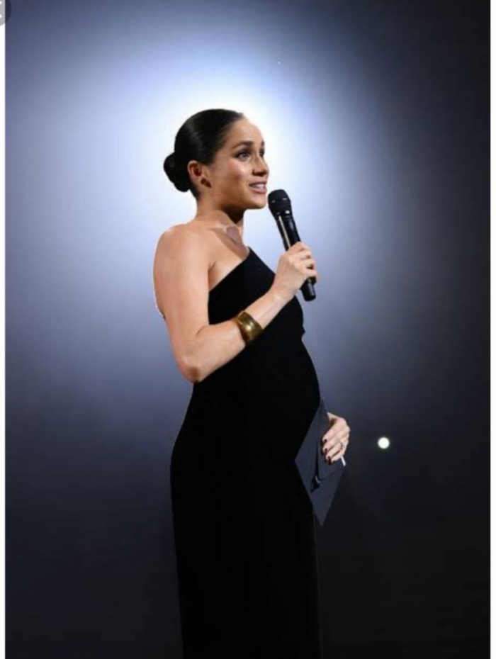 A Duquesa Meghan Markle com um lindíssimo longo preto de uma alça só. Para completar o look, um bracelete (acessório super coringa e muito usado).