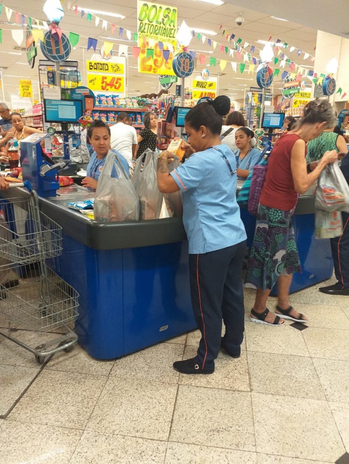 Funcionária de um supermercado guarda as compras em sacolas plásticas