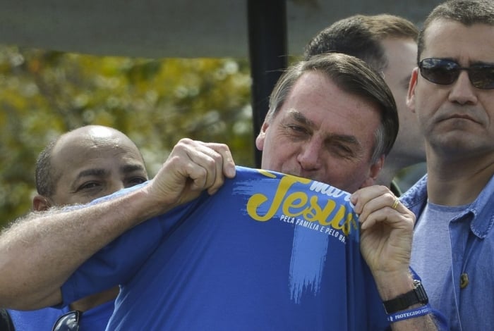 O presidente Jair Bolsonaro beija a camisa da Marcha para Jesus, em Brasília