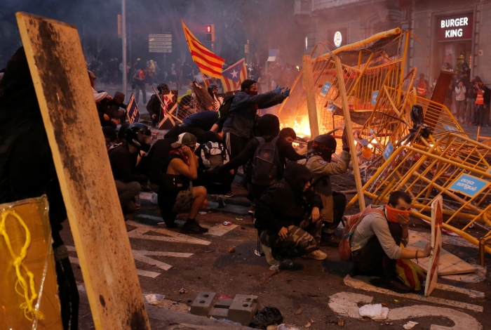 Protesters use fences as a barricade during clashes near the Police headquarters in Barcelona, on October 18, 2019, on the day that separatists have called a general strike and a mass rally. - Spain's protest-hit northeast was gripped by a general strike today as thousands of 