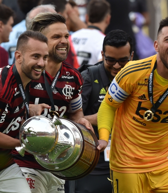 Flamengo's Everton Riveiro (L) and Flamengo's goalkeeper Diego Alves (R) celebrate with the trophy after winning the Copa Libertadores final football match by defeating Argentina's River Plate, at the Monumental stadium in Lima, on November 23, 2019. (Photo by CRIS BOURONCLE / AFP)