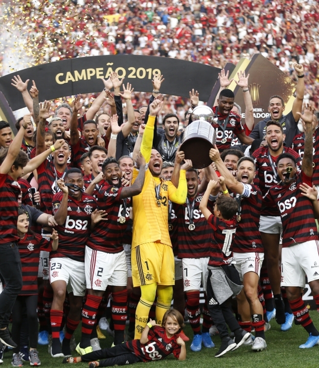 Players of Brazil's Flamengo celebrate on the podium with the trophy after winning the Copa Libertadores final football match by defeating Argentina's River Plate, at the Monumental stadium in Lima, on November 23, 2019. (Photo by Luka GONZALES / AFP)