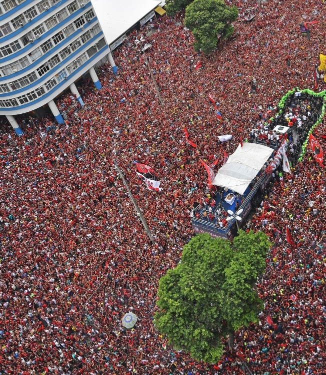 Aerial view of Brazil's Flamengo fans surrounding a bus carrying the Flamengo football team during a celebration parade after their Libertadores Final football match victory against Argentina's River Plate, Rio de janeiro on November 24, 2019. (Photo by CARL DE SOUZA / AFP)
      Caption
