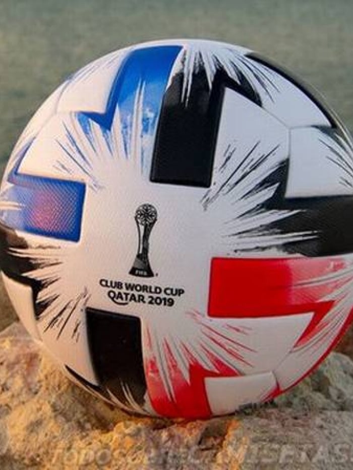 A bola segue com predominância da cor branca, porém com detalhes em vermelho, preto e azul