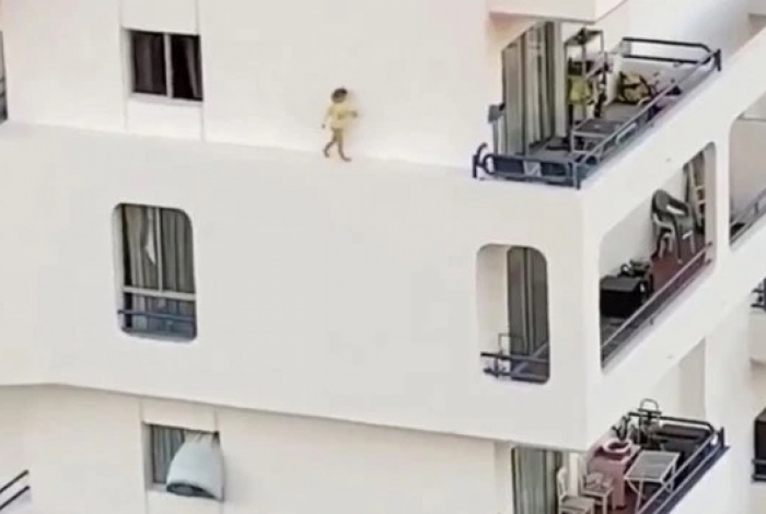 Criança correndo no parapeito do prédio