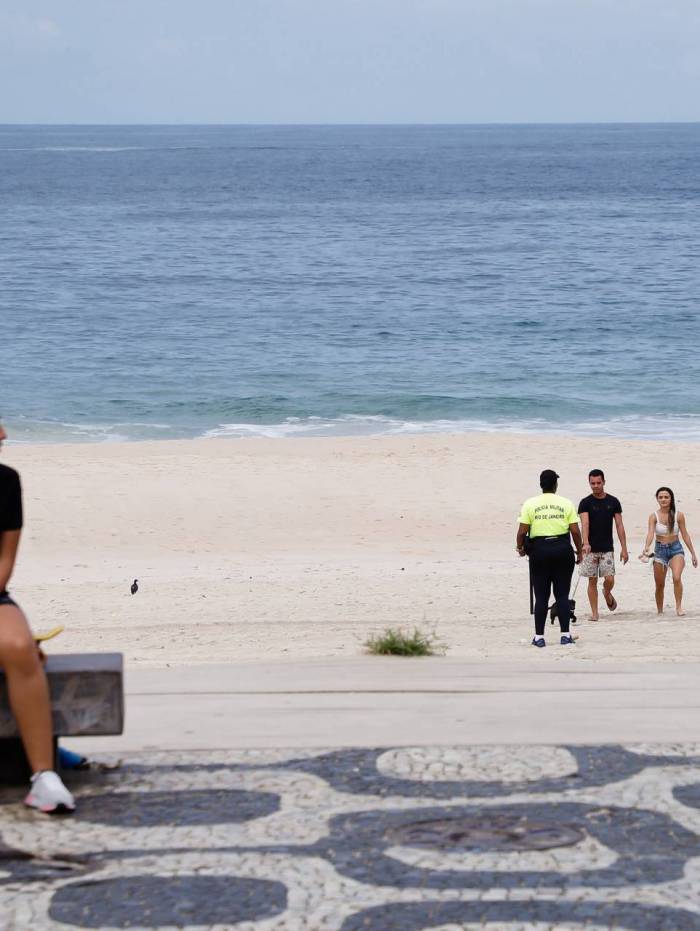 Clima tempo. Movimentacao reduzida em praias da Zona Sul, na manha deste domingo (22). Policial militar orienta pessoas para que saiam da areia da praia, em Ipanema.