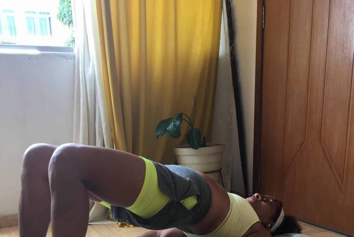 Vera Lucia Serino dos Santos, de 72 anos, aproveita os espaços da sala para praticar sua série: elevação de quadril (6), abdominal (7), Agachamento alternado (8) e Agachamento em Isometria (9) 
