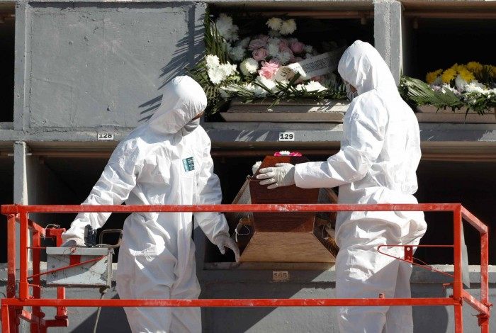Coveiros usando roupas e equipamentos de proteção sepultam mais uma vítima da Covid-19 no Rio
