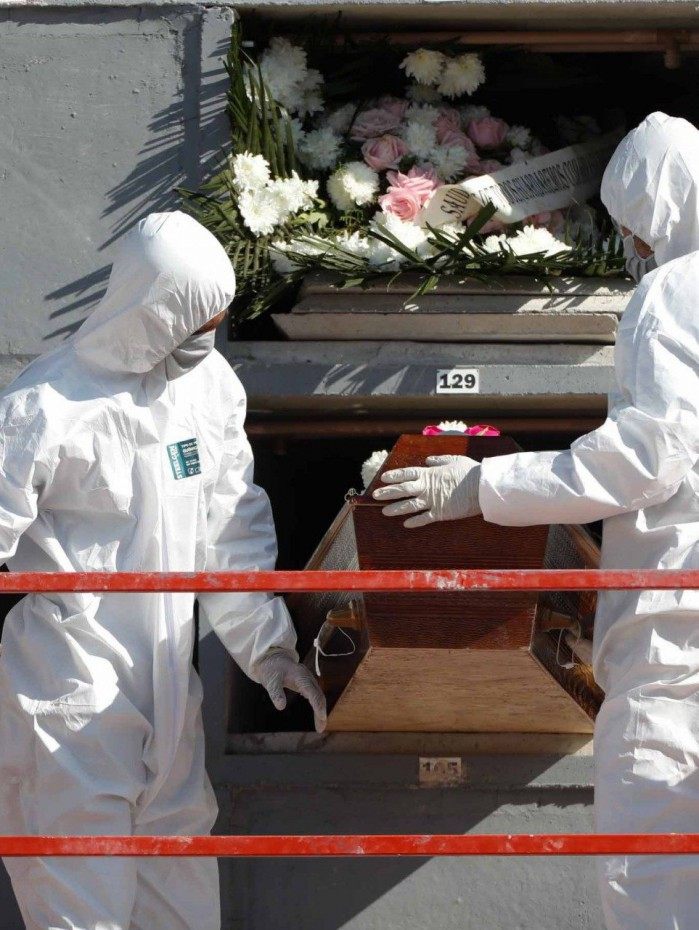 Coveiros usando roupas e equipamentos de prote&ccedil;&atilde;o sepultam mais uma v&iacute;tima da Covid-19 no Rio