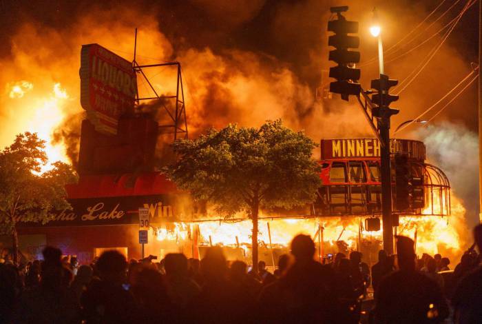 Manifestantes se reúnem em torno de uma loja em chamas em Minneapolis, Minnesota, durante um protesto pela morte de George Floyd