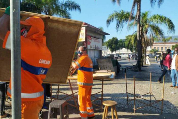 Funcionários da Comlurb desmontam barracas em ação contra comércio não essencial na Praça Procópio Ferreira, na Central do Brasil