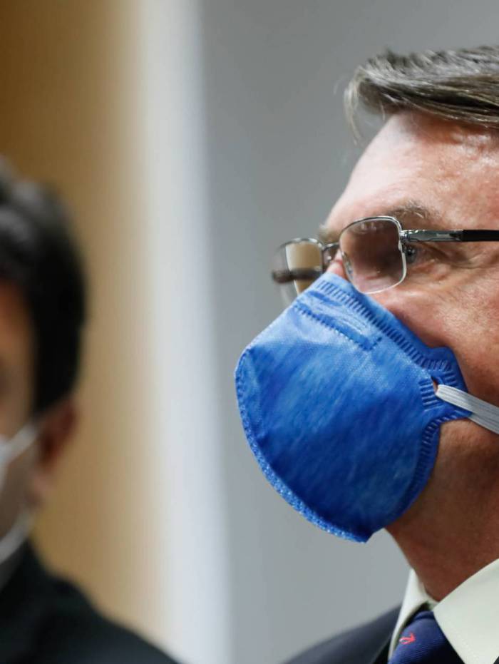 Luiz Henrique Mandetta (ao fundo) e Jair Bolsonaro: troca de farpas
