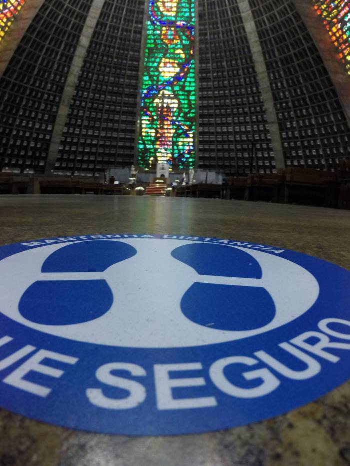 Assentos e lugar na fila da comunhão são sinalizados com dois metros de distância entre os fiéis