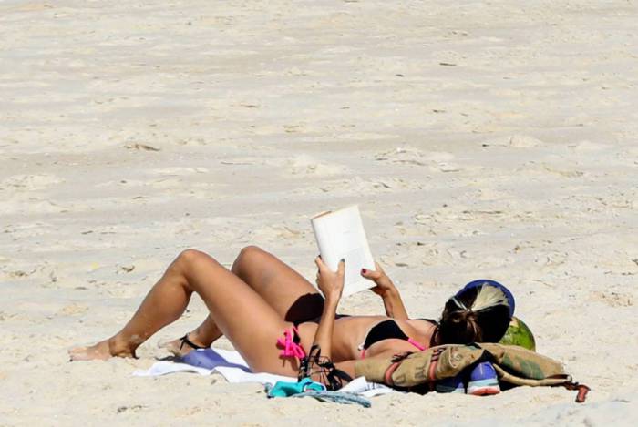 Júlia Oristânio vai a praia com seu pet e aproveita para ler um livro