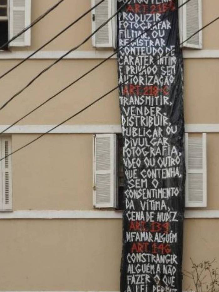 Mulher &eacute; fotografada nua pelos vizinhos e pendura faixa de protesto na janela