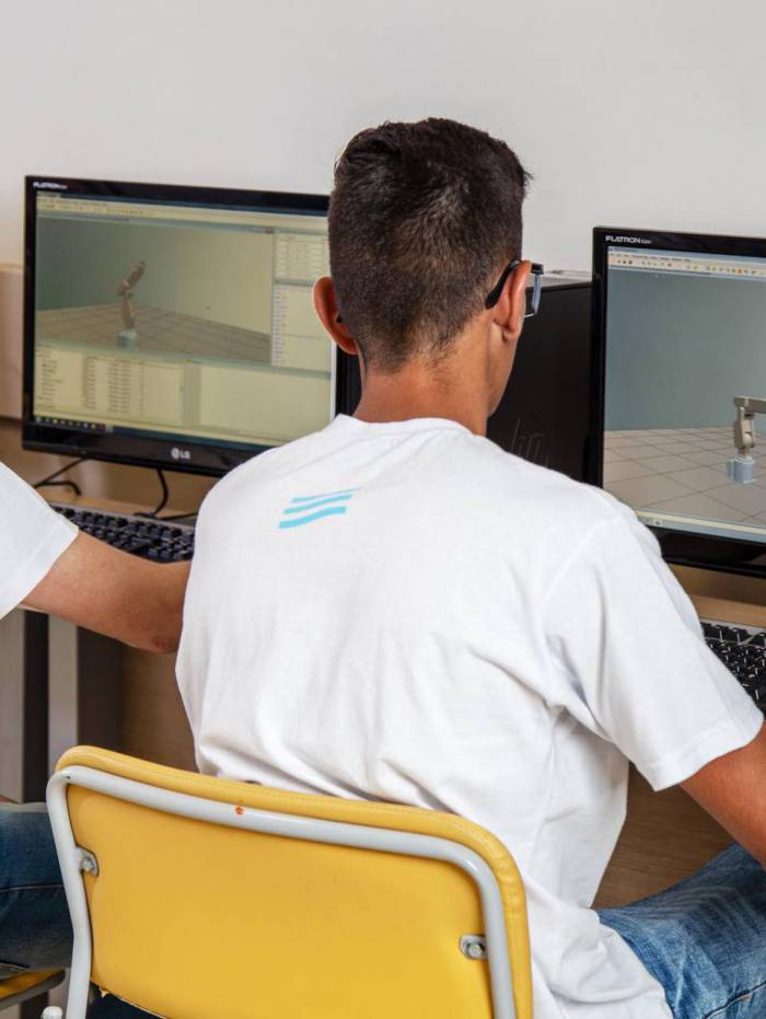  Alunos do SENAI mecatr&ocirc;nica operando bra&ccedil;o rob&oacute;tico no computador. Da esquerda para a direita:  os alunos Reginaldo Medeiros da S. Junior e Lucas Guilherme Piassa Ferreira.