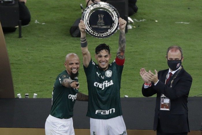 Palmeiras' captains, Paraguayan Gustavo Gomez (C) and Felipe Melo,  celebrate with a trophy after winning the Copa Libertadores football tournament by defeating Santos in the all-Brazilian final match at Maracana Stadium in Rio de Janeiro, Brazil, on January 30, 2021. (Photo by Silvia Izquierdo / POOL / AFP)