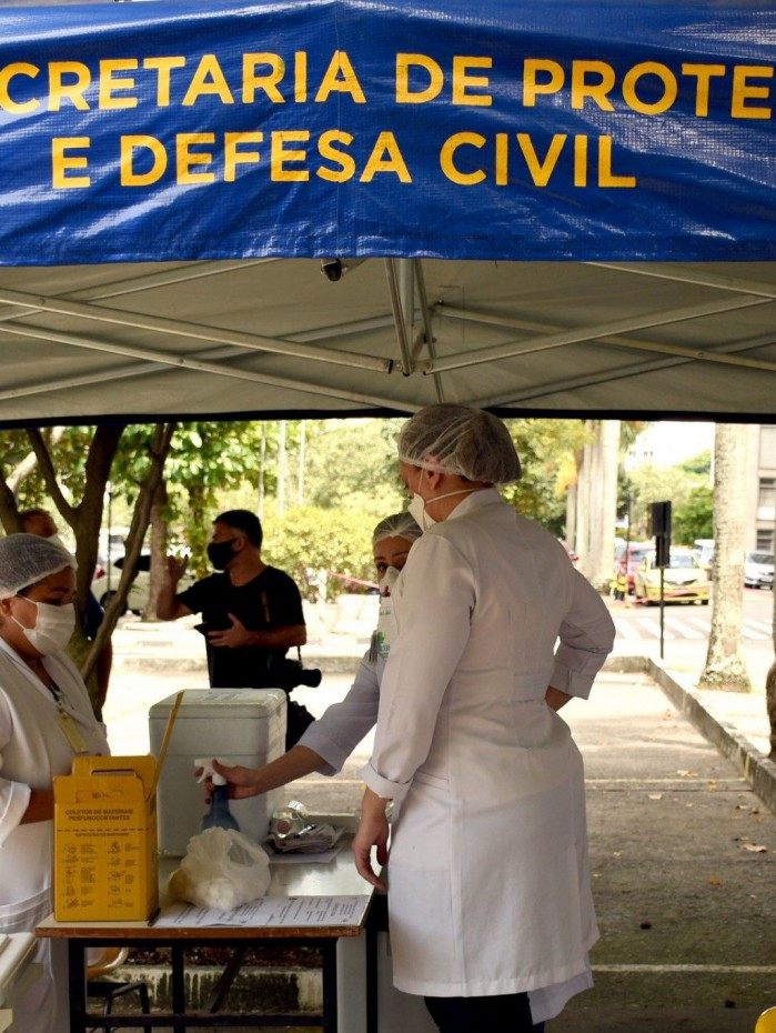 Profissionais abaixo de estande de vacina&ccedil;&atilde;o, em estacionamento, na Uerj
