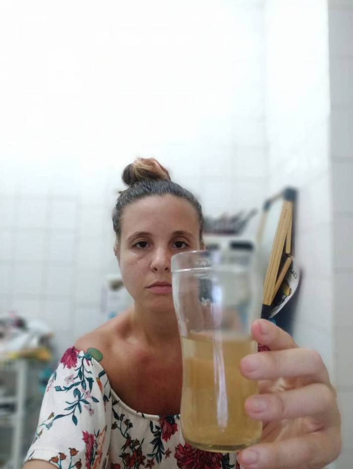 Júlia Vieira, moradora da Lapa, mostra como a água tem saído da torneira