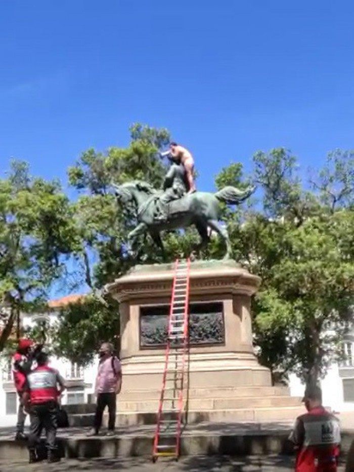 Nu, homem sobe em est&aacute;tua e se nega a descer at&eacute; ser vacinado