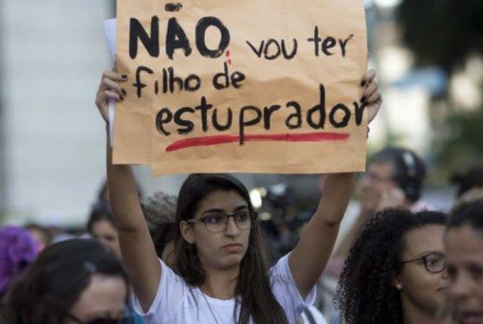 Mulher levanta cartaz contra gravidez forçada