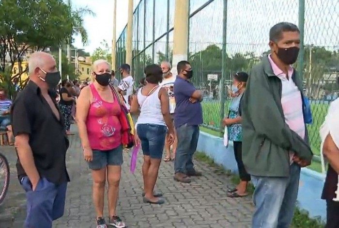 Na manhã desta quarta (14), uma longa fila havia se formado em um dos locais de vacinação para a obtenção da primeira dose do imunizante na Praça do Galo, em Duque de Caxias, na Baixada Fluminense