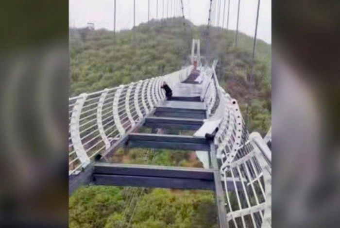Turista se segura em ponte de vidro quebrada na montanha Piyan