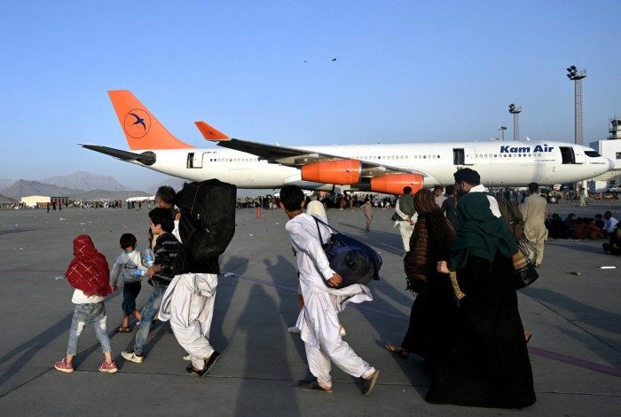 Famílias afegãs caminham perto das aeronaves no aeroporto de Cabul 