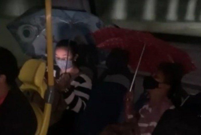 Passageiras usam guarda-chuva para se proteger dentro de BRT
