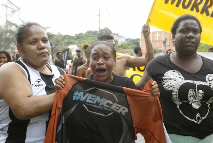 Em uma manifestação, Caroline Camargo, irmã do adolescente, segura a camisa que ele vestia no momento em que foi baleado