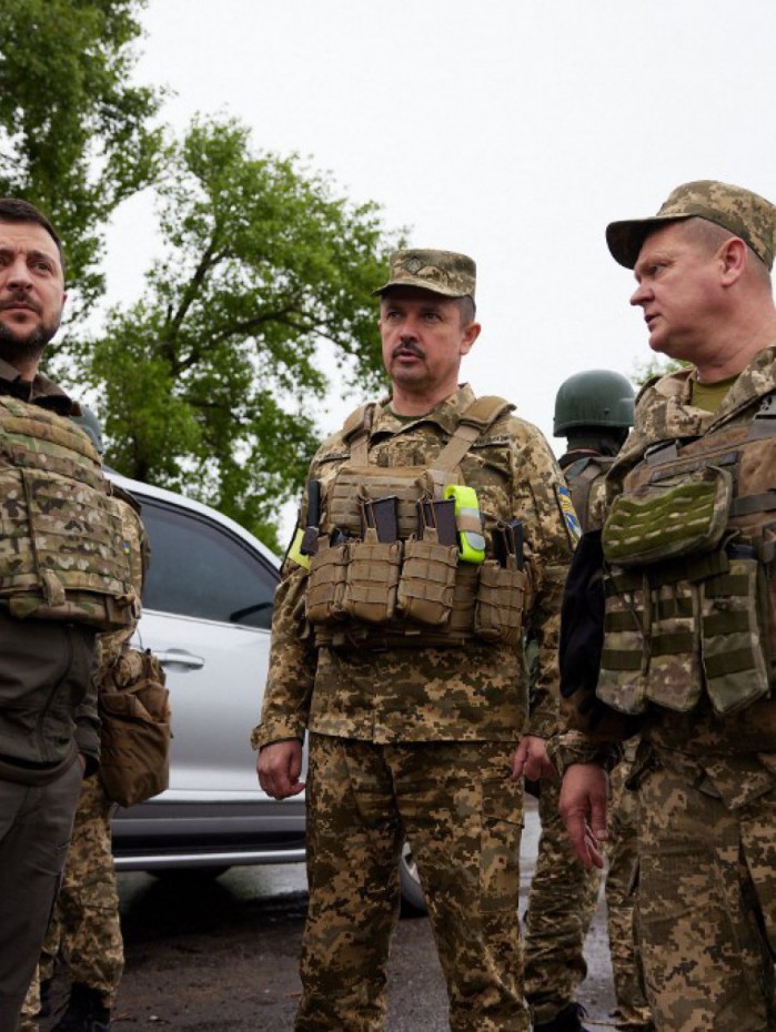 Volodymyr Zelensky usando colete à prova de balas acompanhados por soldados ucranianos