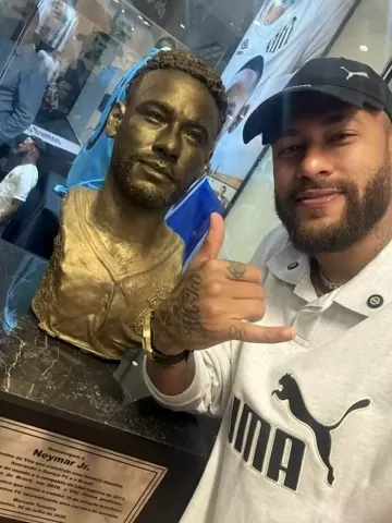 Neymar ao lado do busto que recebeu, no Memorial das Conquistas, do Santos